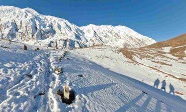a group of three person taking picture of trail covered with snow enroute to Tilicho lake trek